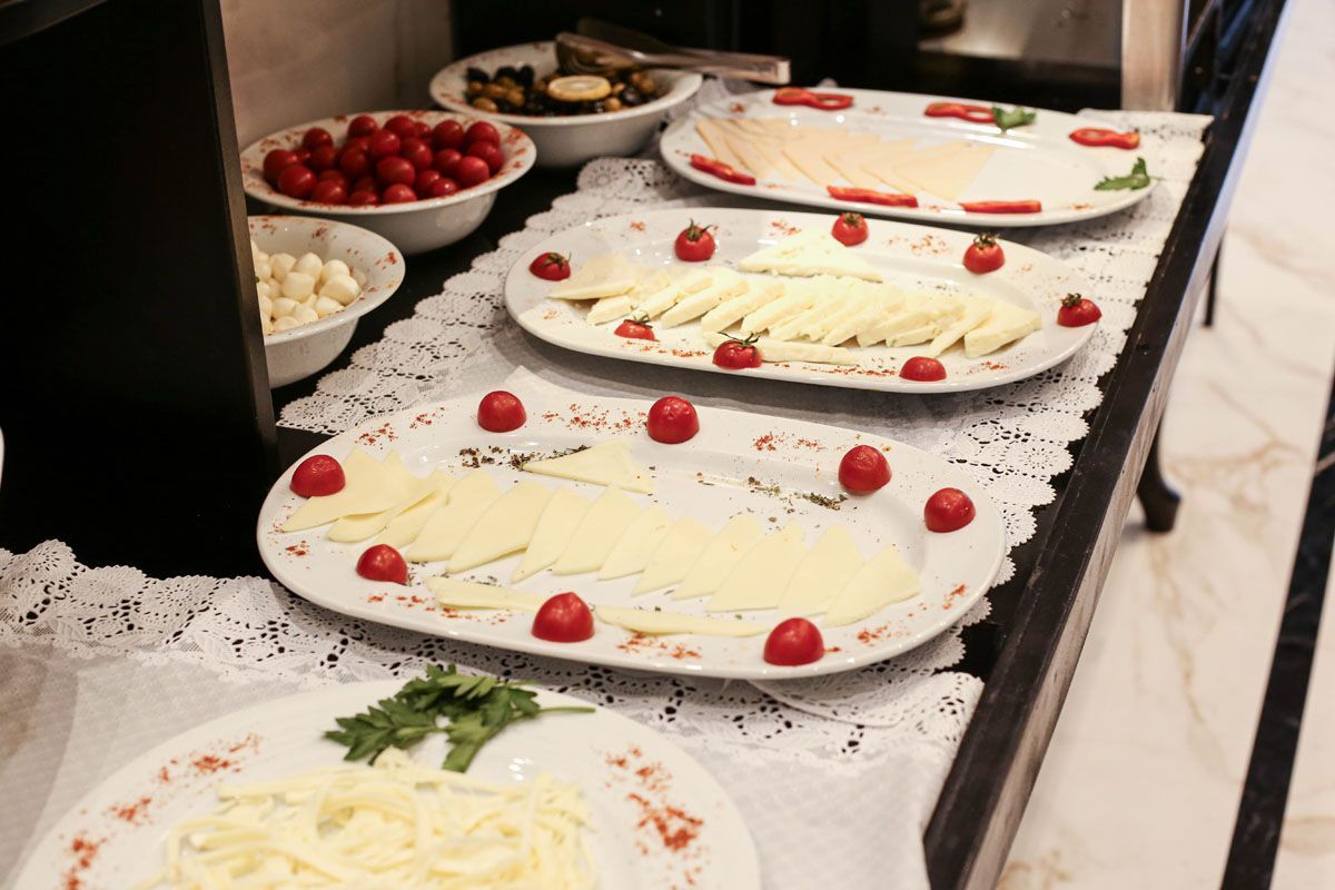 Dessert buffet with trays of white frosted cakes topped with strawberries on a black countertop