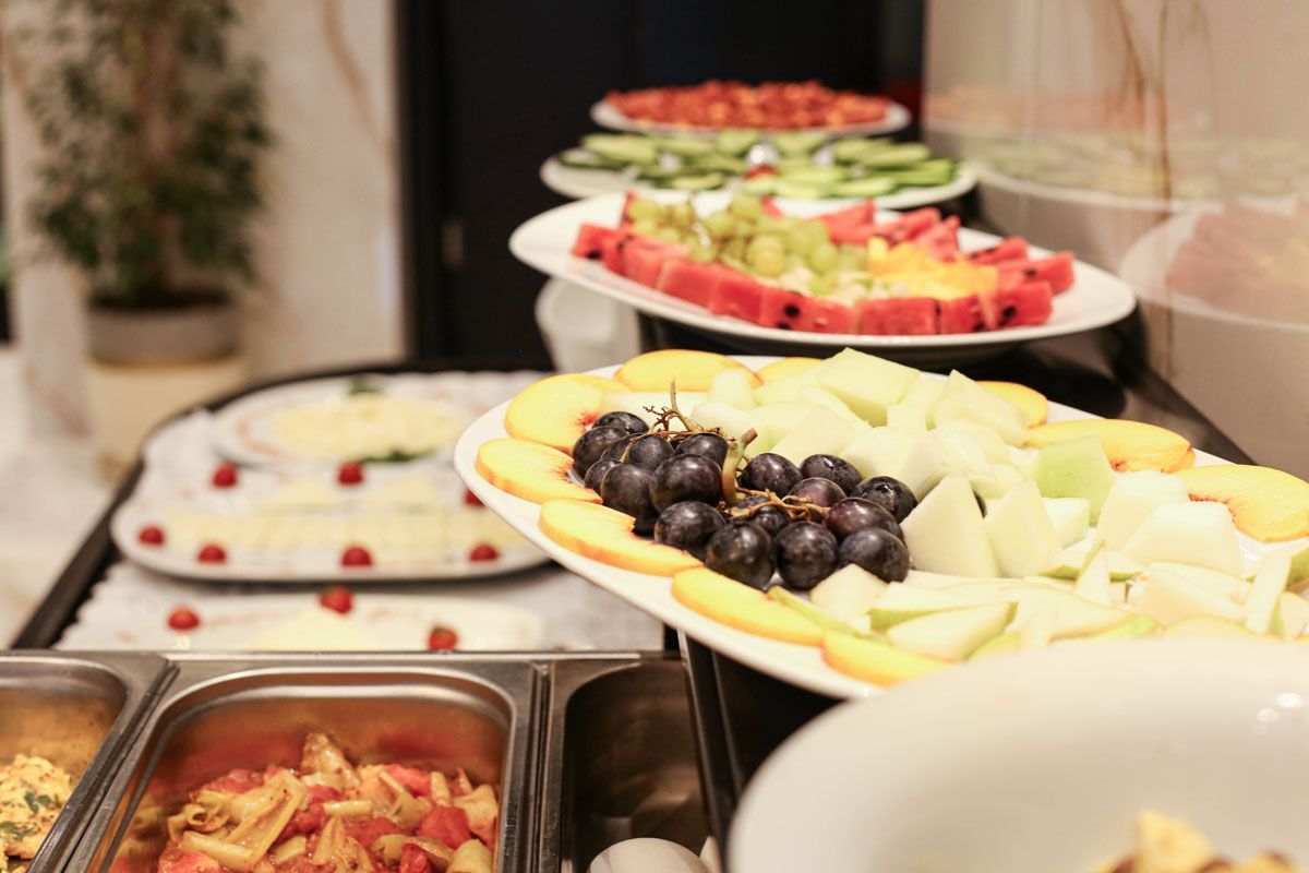 Buffet table with trays of fruit platters, grapes, melon, and watermelon slices