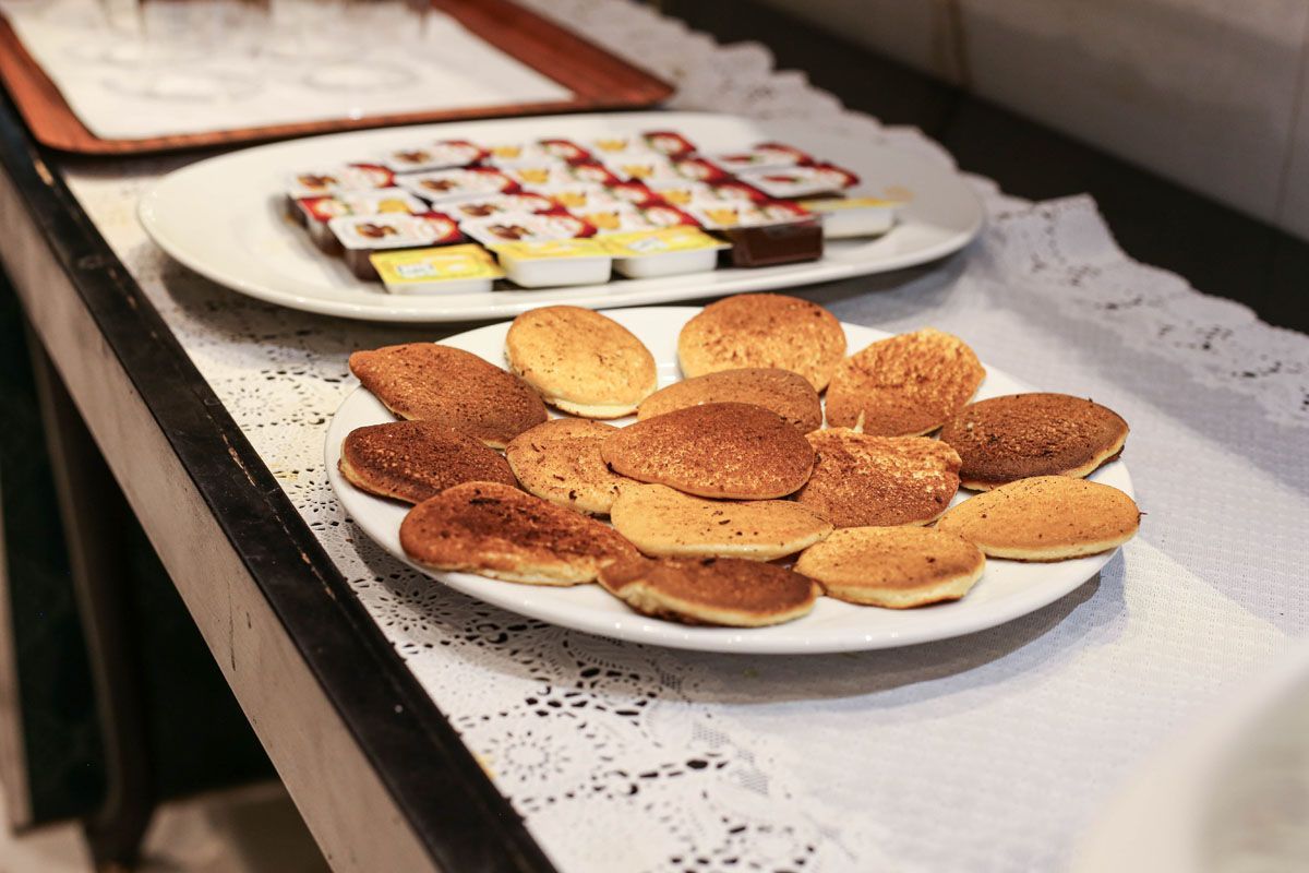 Plates of assorted cookies and pastries on a table with a lace runner