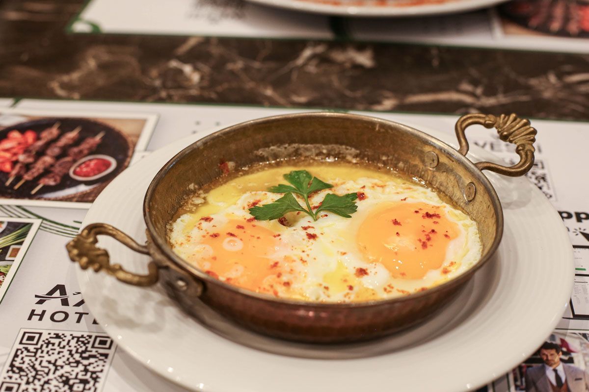 Baked egg dish in a rustic bowl on a white plate, garnished with herbs and spices