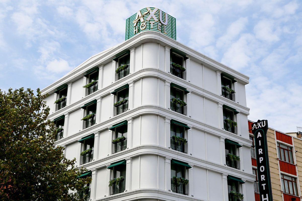 White multi-story building with green accents and a rooftop sign against a cloudy sky
