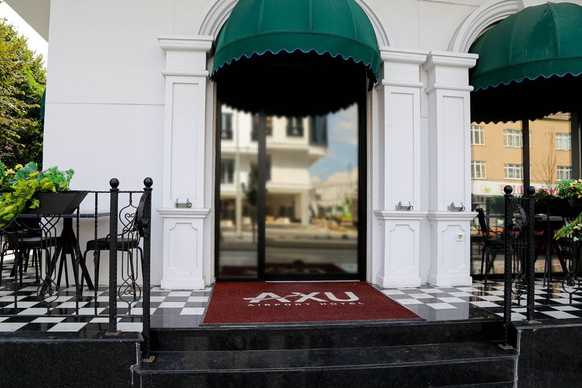 Building entrance with green awnings, red doormat, and black-and-white tiled patio