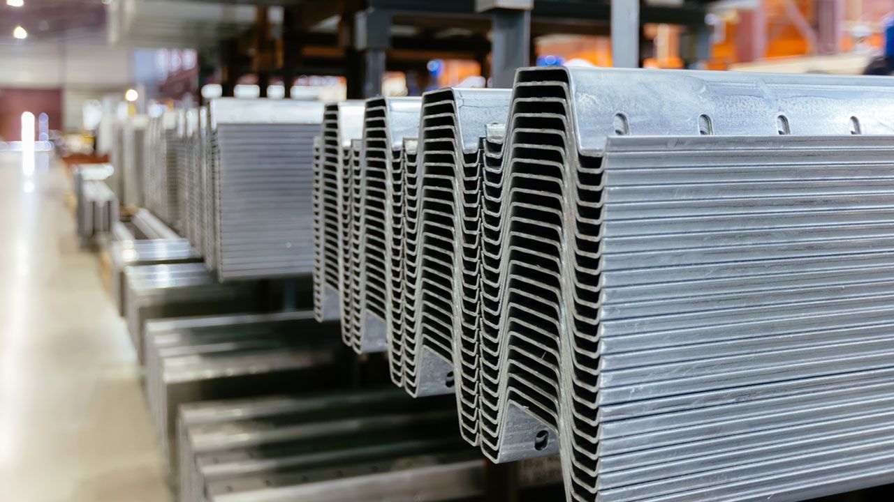 A row of formed and punched metal parts sitting neatly on top of each other in a warehouse.