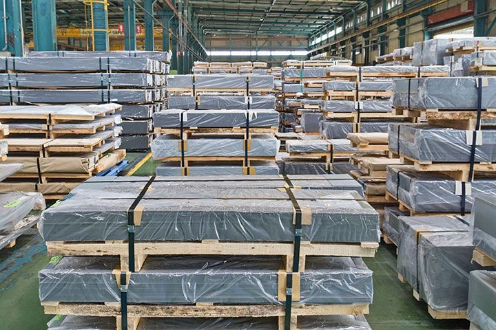 A clean and organized warehouse filled with lots of metal sheets wrapped in plastic.