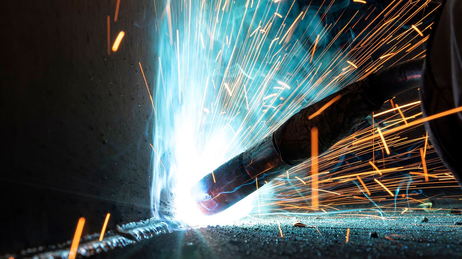 A close up of a worker welding two pieces of metal together.