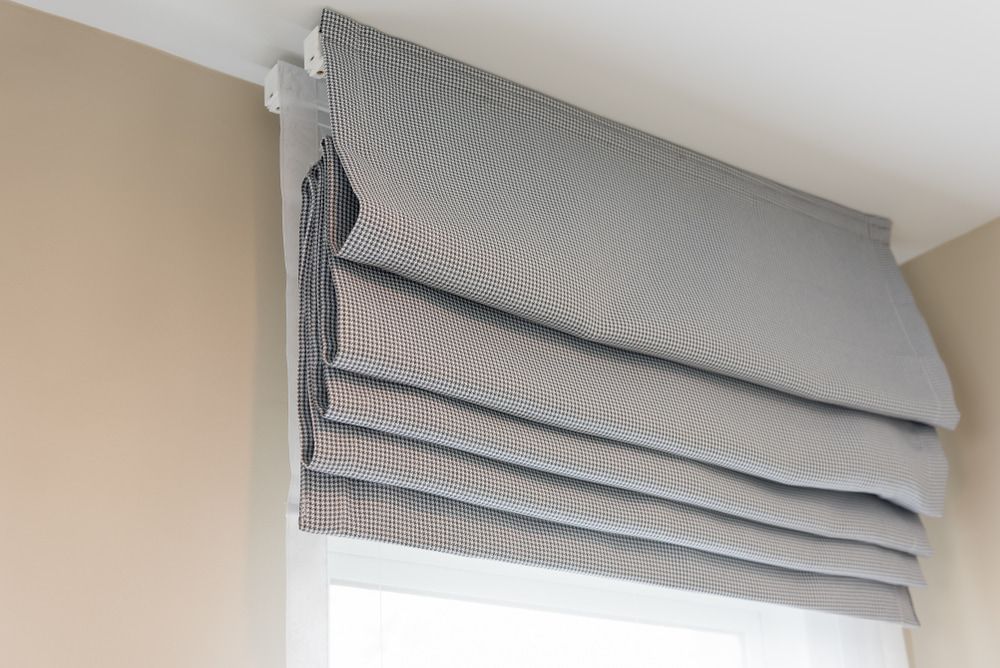 A Gray Roman Shade Is Hanging From The Ceiling Above A Window —  Cabonne Carpets In Molong, NSW