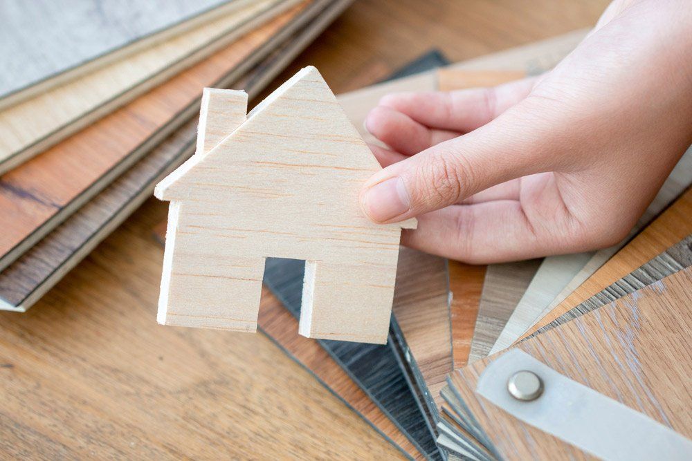 A Person Is Holding A Small Wooden House In Their Hand —  Cabonne Carpets In Molong, NSW
