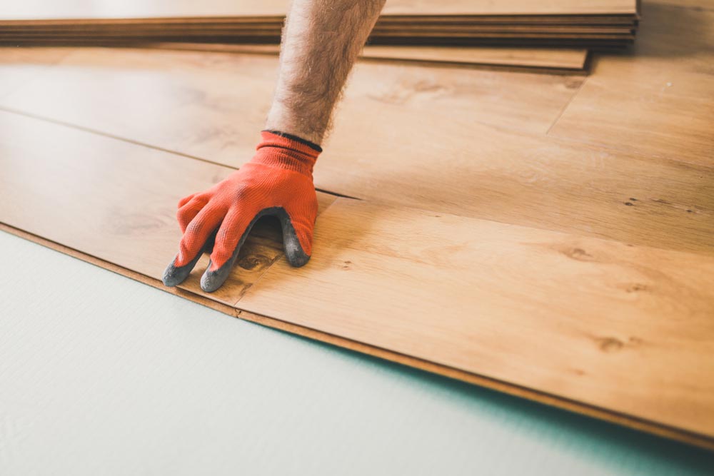 A Person Wearing Orange Gloves Is Installing A Wooden Floor —  Cabonne Carpets In Molong, NSW