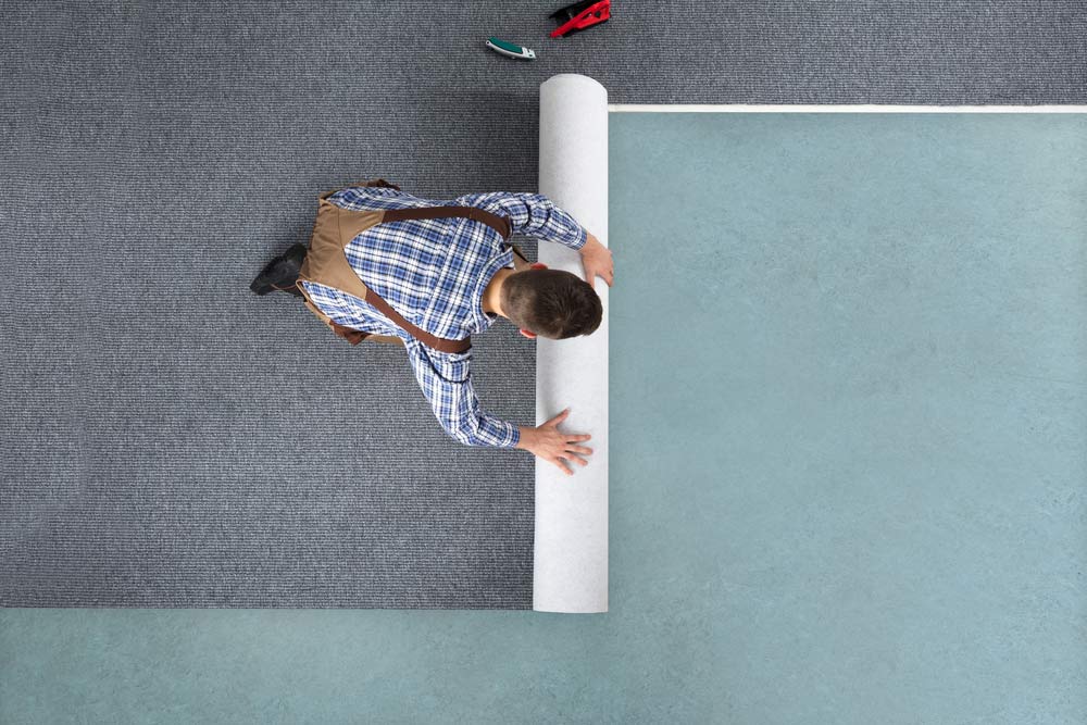 Male Rolling Out New Grey Carpet —  Cabonne Carpets In Molong, NSW