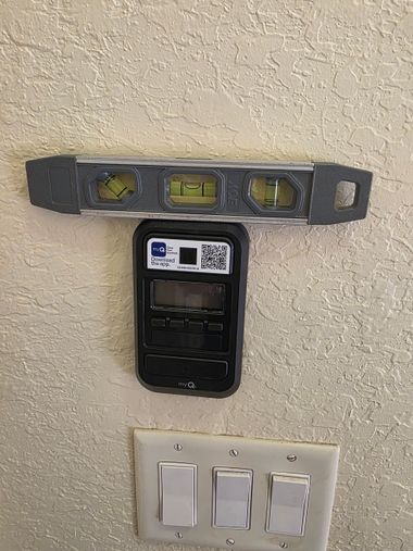 Wall with a level, phone mount, and three light switches.