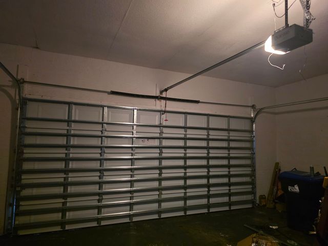 Empty garage with a closed sectional garage door and an overhead garage door opener.