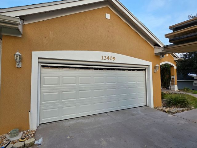 Closed tan garage door with house number 13409 on a stucco home exterior
