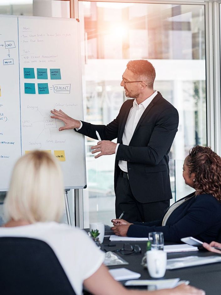 A man in a suit is giving a presentation to a group of people.