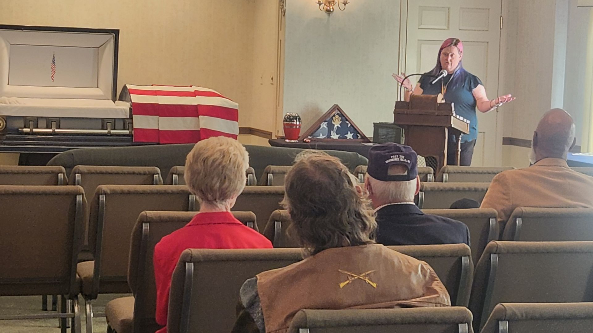 Woman speaking at a veterans resource fair, educating attendees about burial rights and benefits.