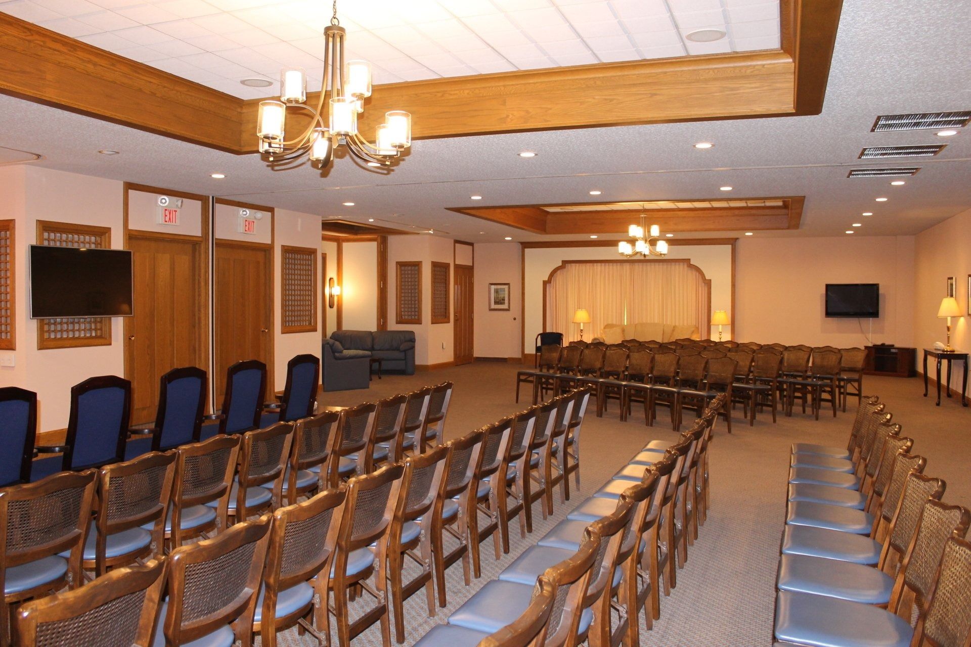 Rows of chairs face a stage in a formal room, possibly a chapel or auditorium.