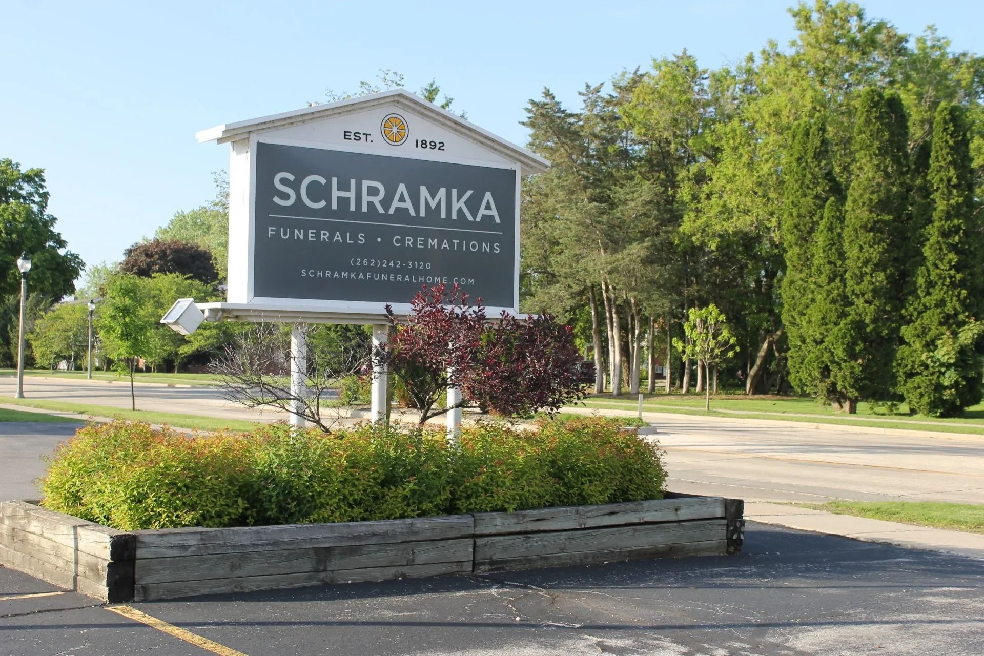 Schramka Rentals & Creations sign, white with black lettering, in front of greenery.