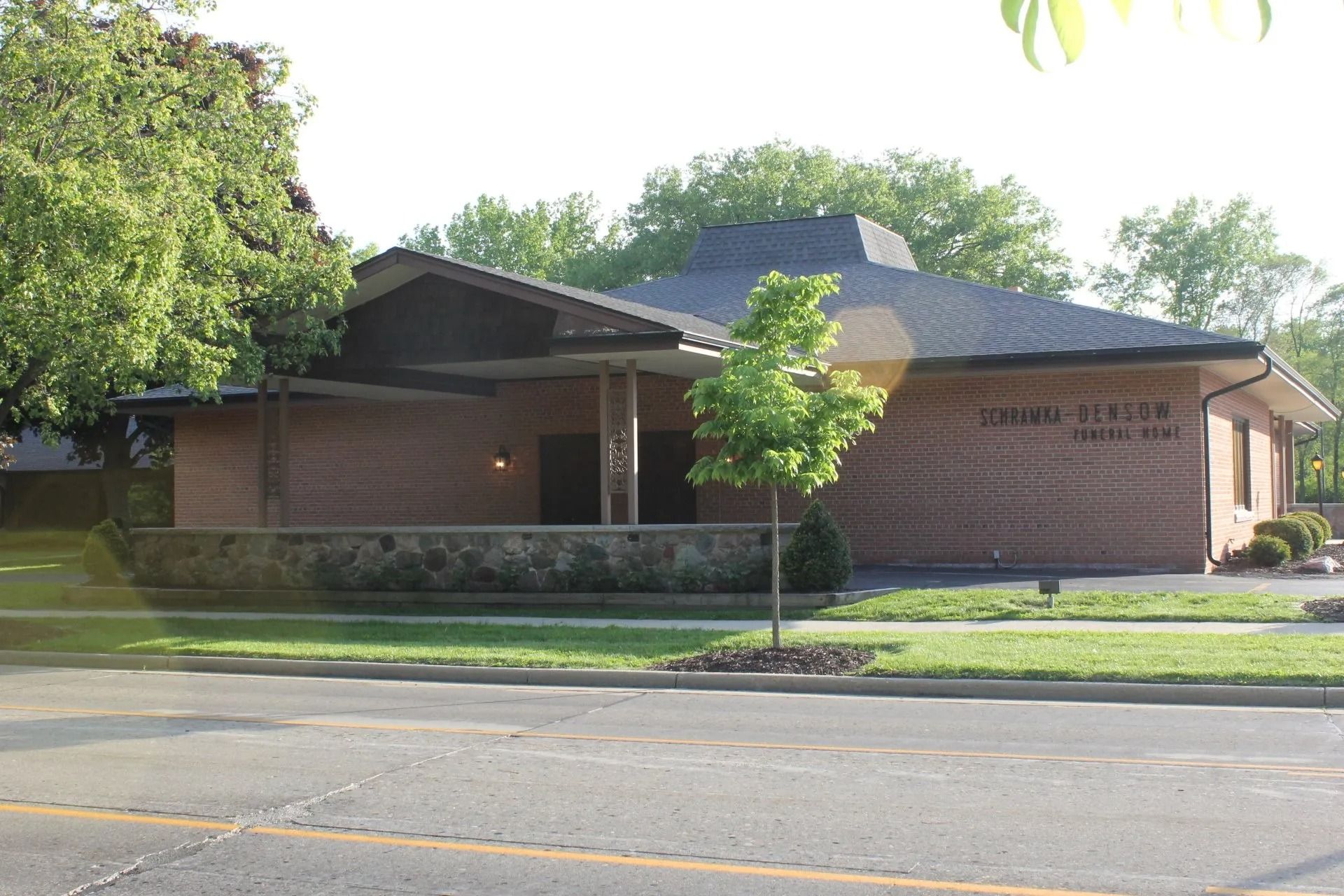 Brick building with a dark roof and sign reading