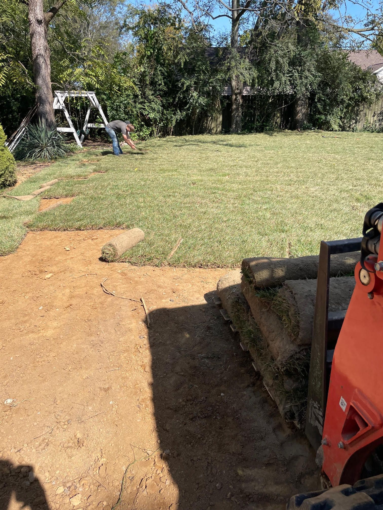 A man is working on a stump grinder in a backyard.