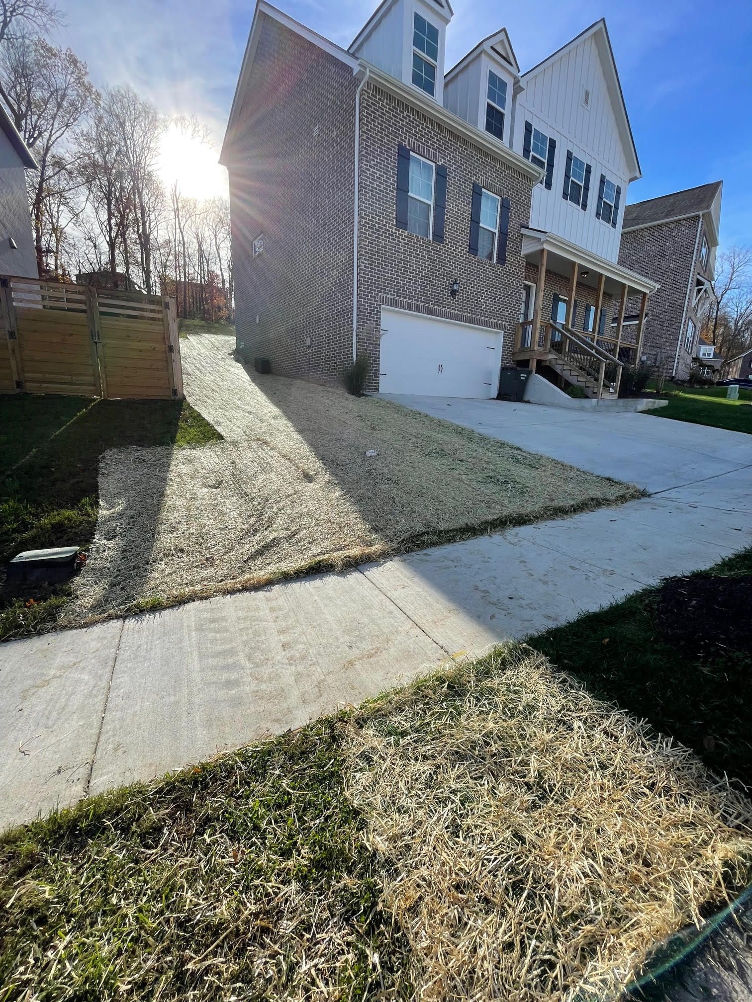 A large brick house with a driveway and a sidewalk in front of it.