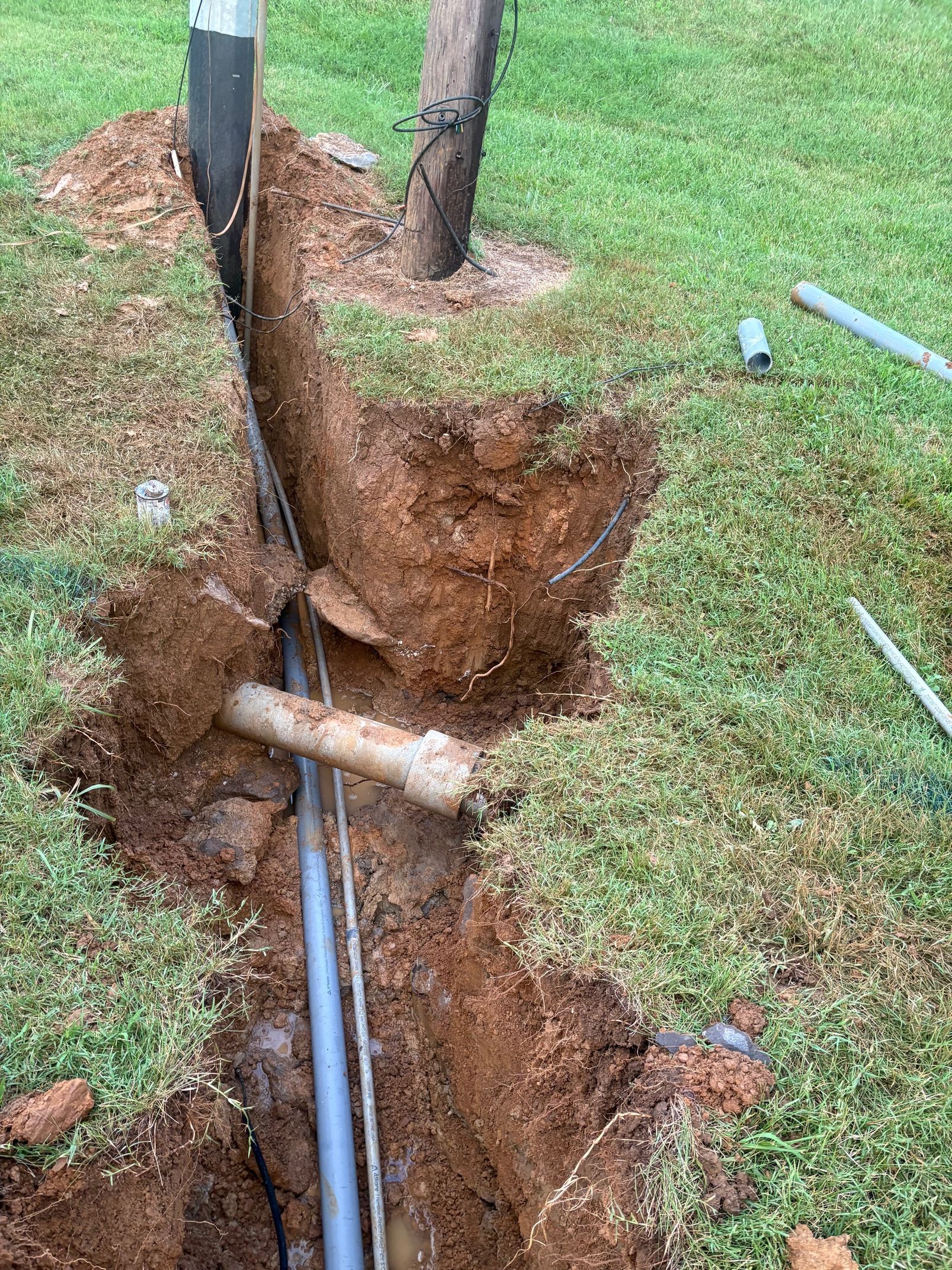 A man is digging a hole in the ground next to a fence.
