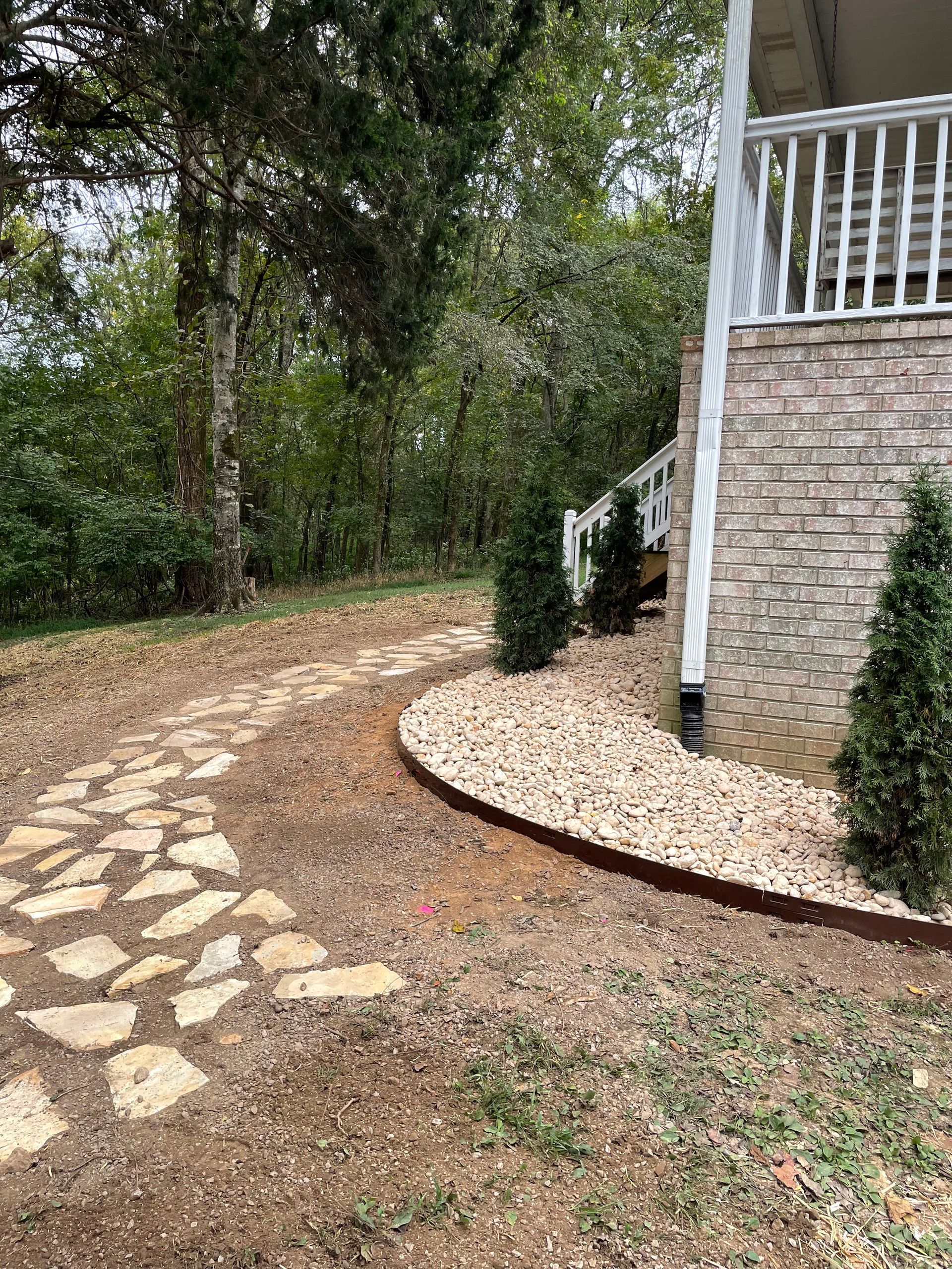 A stone walkway leading to a house with a porch.