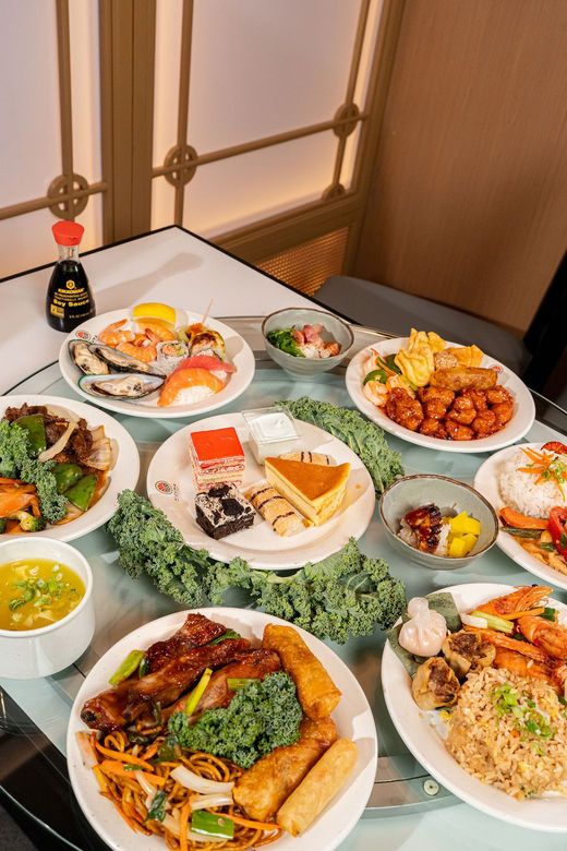 A table covered with assorted plated dishes in a restaurant setting, including grilled meats, vegetables, and rice.
