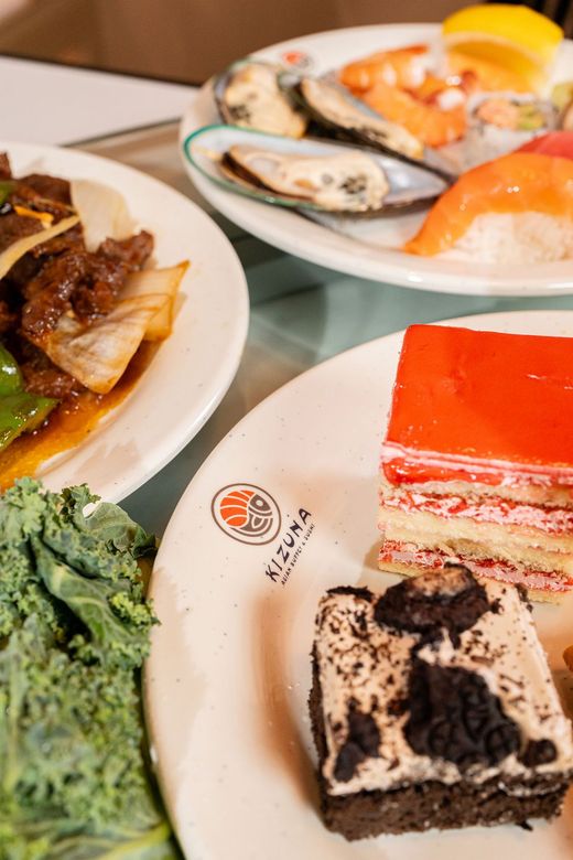 Buffet table with seafood, salad, and colorful desserts on white plates