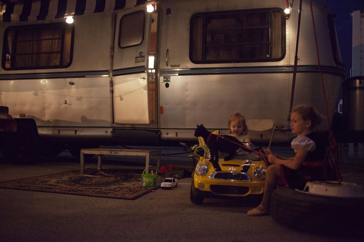 Circus kids hang out with their cat while their parents work the show.