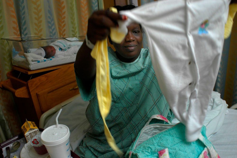 Sawson holds up the baby clothes that her new baby girl, Amma, will wear when they leave the hospital. 'She's beautiful,' said Sawson. 'I am happy.'