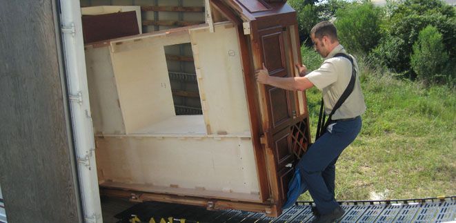 A man is lifting a piece of furniture out of a truck from Cupboard Wagon cabinet delivery services