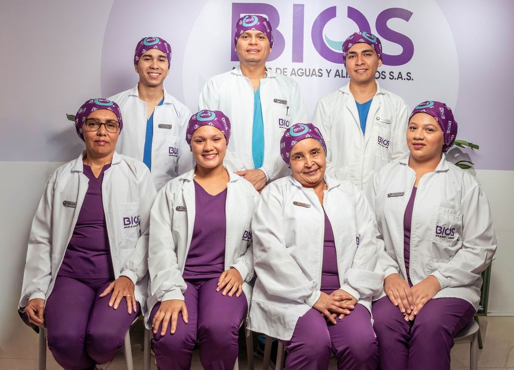 Siete miembros del personal médico, vestidos con batas blancas y uniformes morados, posan en el vestíbulo de una clínica.