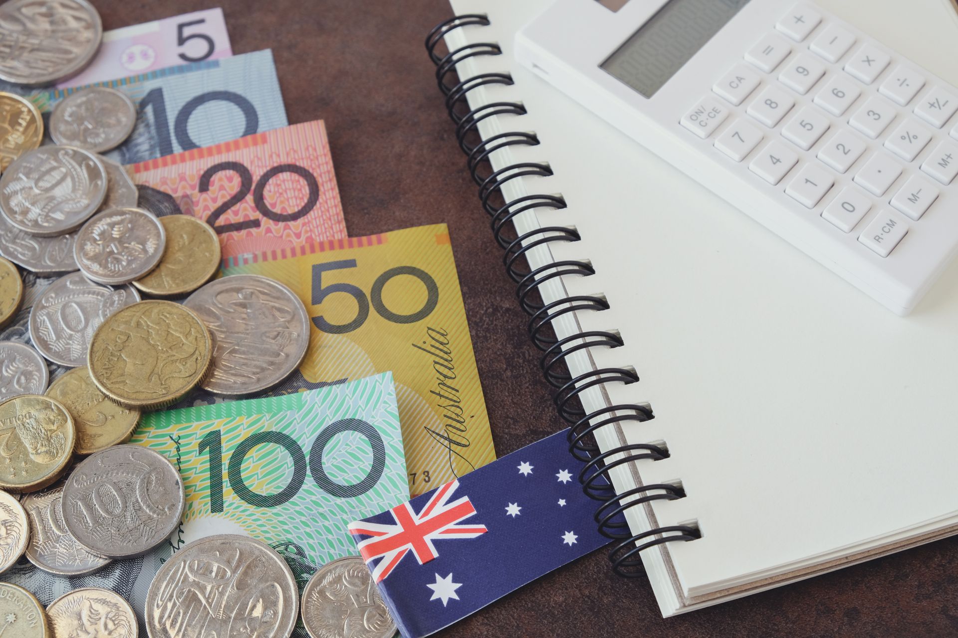 Australian currency, coins and notes, with a calculator, notepad, and flag. Australian currency, coins and notes, with a calculator, notepad, and flag.