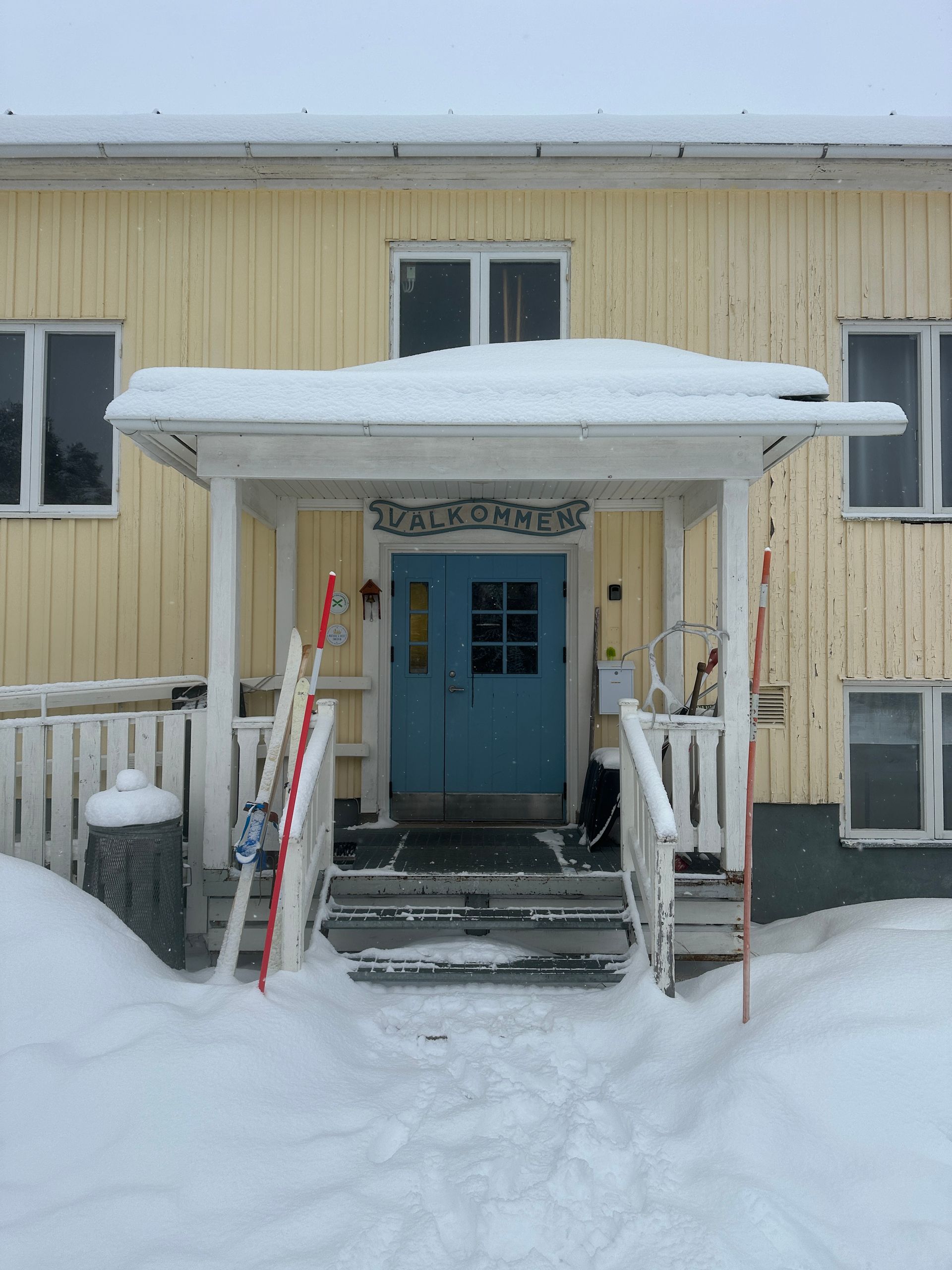 Snow-covered apartment entrance with blue door and white porch steps