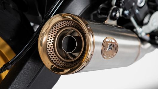 Tubo di scarico per motocicletta con estremità color oro e corpo in metallo, fissato al telaio nero della motocicletta.