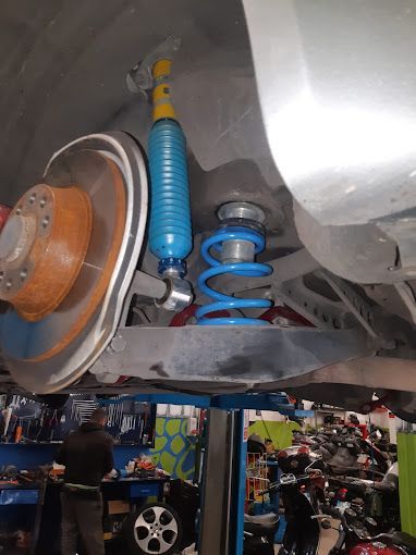 Sistema di sospensioni blu installato sulla ruota posteriore di un'auto, in un ambiente di officina.
