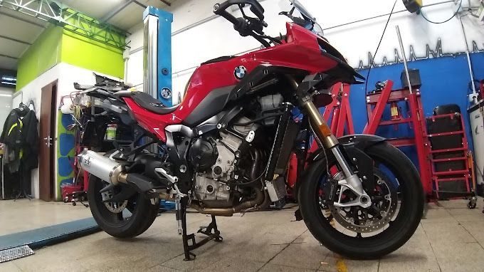 Motocicletta BMW rossa e nera in un'officina, parzialmente smontata.