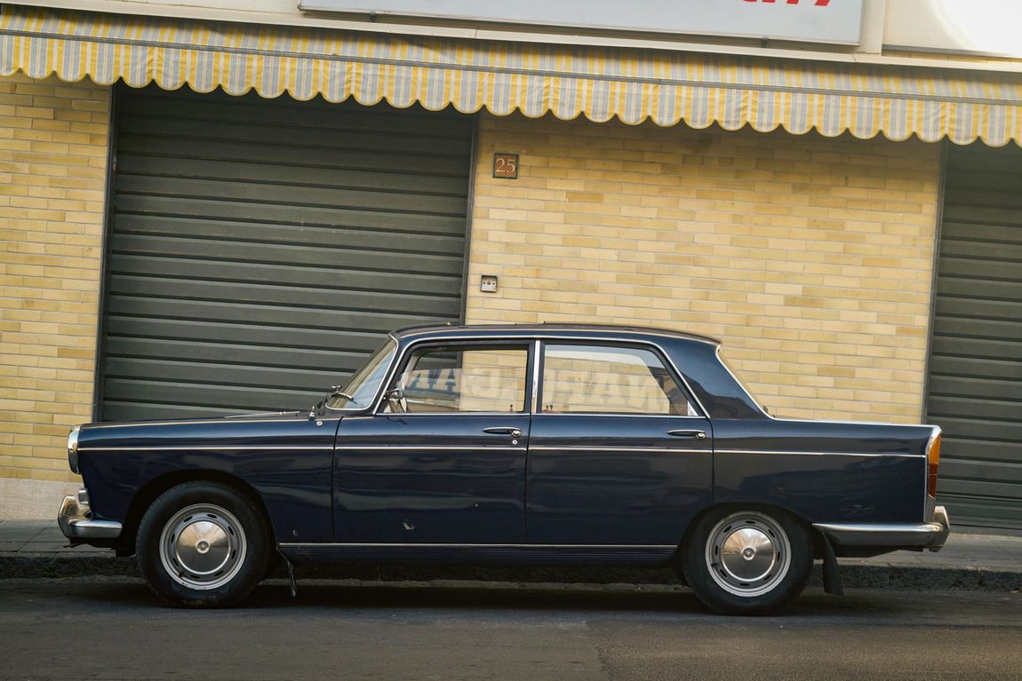 A blue car is parked in front of a brick building