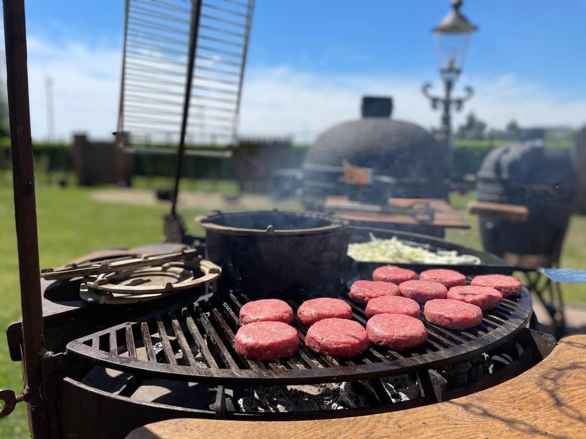 Hamburgers die op een zonnige dag buiten op een metalen grill worden gegrild.