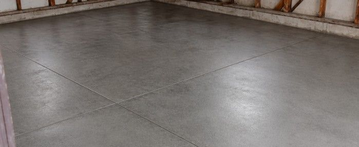 Plain bare concrete floor in an unfinished garage space, showing a clean but visually plain surface that can make the area feel incomplete and less polished.