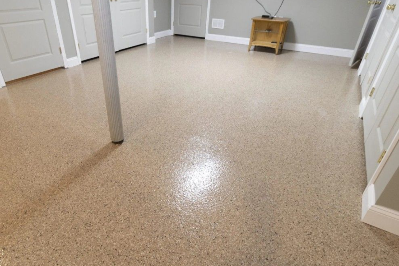 A freshly painted solid light gray epoxy garage floor with matching baseboards and white walls.