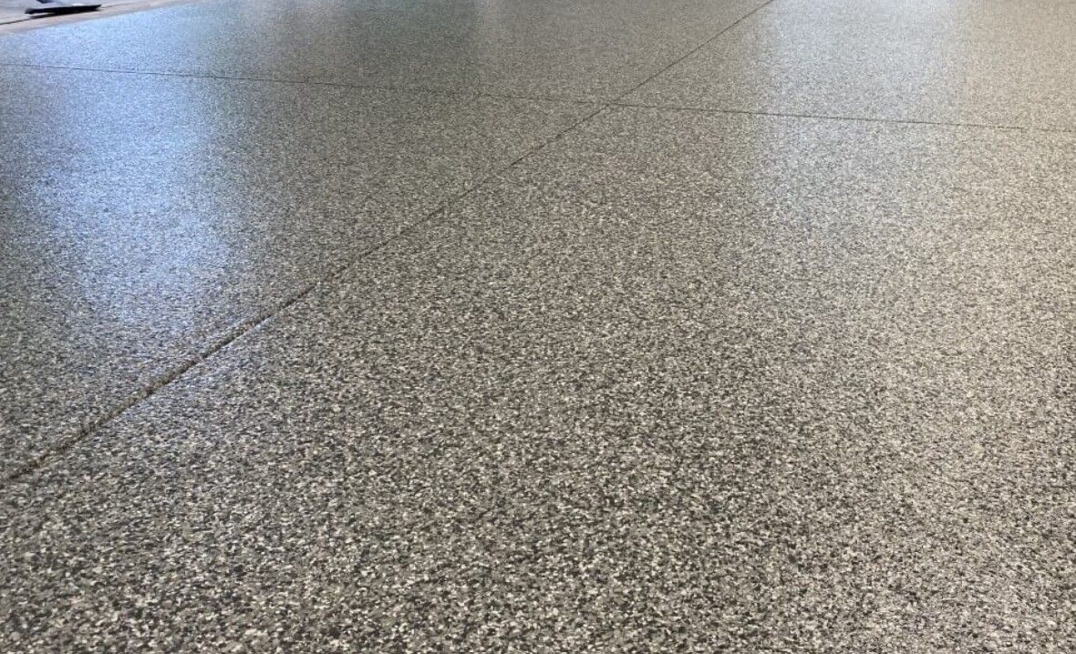 Clean flake floor coating in a garage showing a smooth finished surface built for easier day-to-day maintenance. Clean flake-coated garage floor with a smooth finished surface and organized layout, showing how flake flooring creates a space that looks easier to maintain and keep clean day to day.