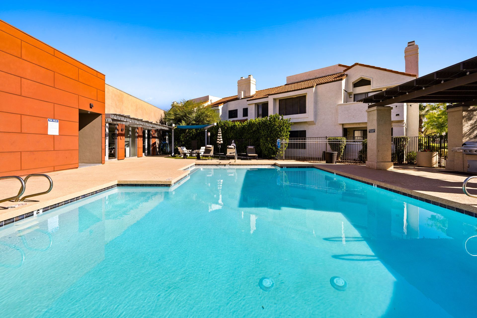 Swimming pool in a courtyard, flanked by buildings with tan stucco, blue sky overhead. Explore inviting Tempe, Arizona apartments at Talavera Apartments today.