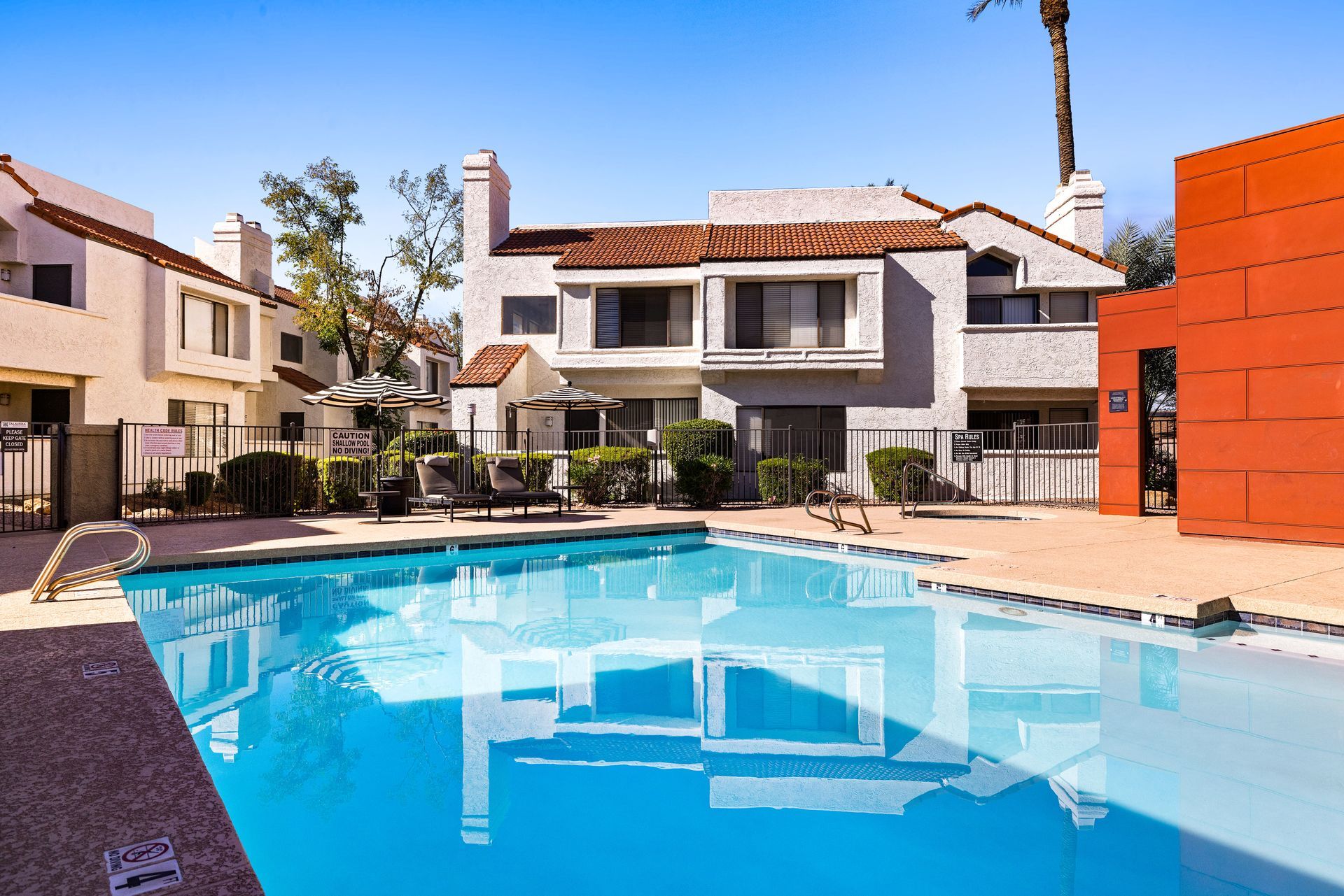Swimming pool in front of two-story apartment buildings on a sunny day. Talavera Apartments offers stylish apartments in Tempe AZ—find your fit.