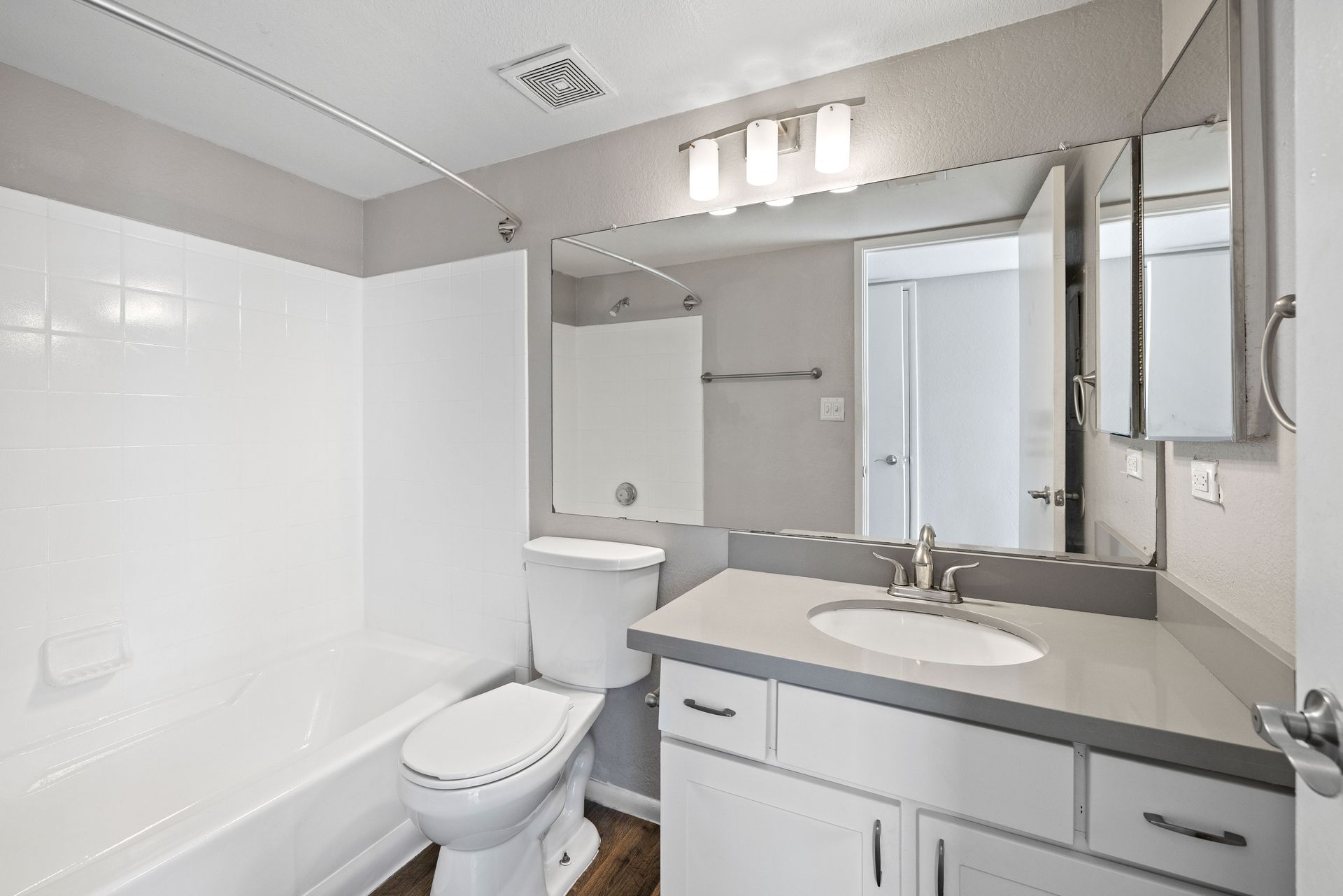 Bathroom with white fixtures, gray counter and walls, mirror, and cabinet. Discover convenient 1 bedroom apartments in Tempe AZ at Talavera Apartments.