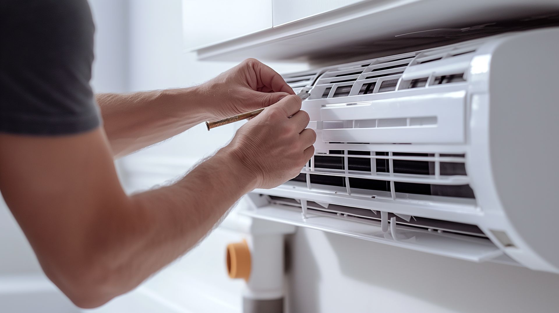 Un homme nettoie le filtre d'un climatiseur.