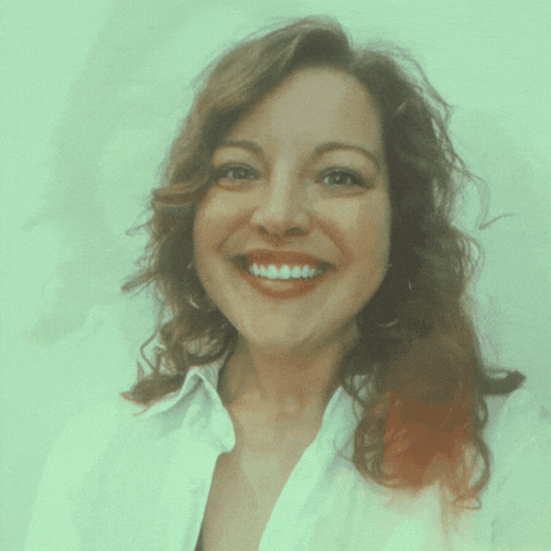 Woman smiles with teeth showing, wearing a white shirt against a green-tinted background.