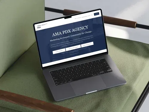 Laptop displaying the AMA PDX AGENCY website on a green chair.