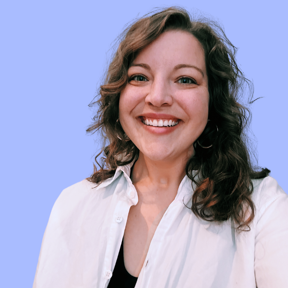 Woman smiling, wearing white shirt, black top, and hoop earrings, on a blue background.