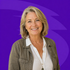 Smiling woman in a white shirt and olive jacket against a purple background