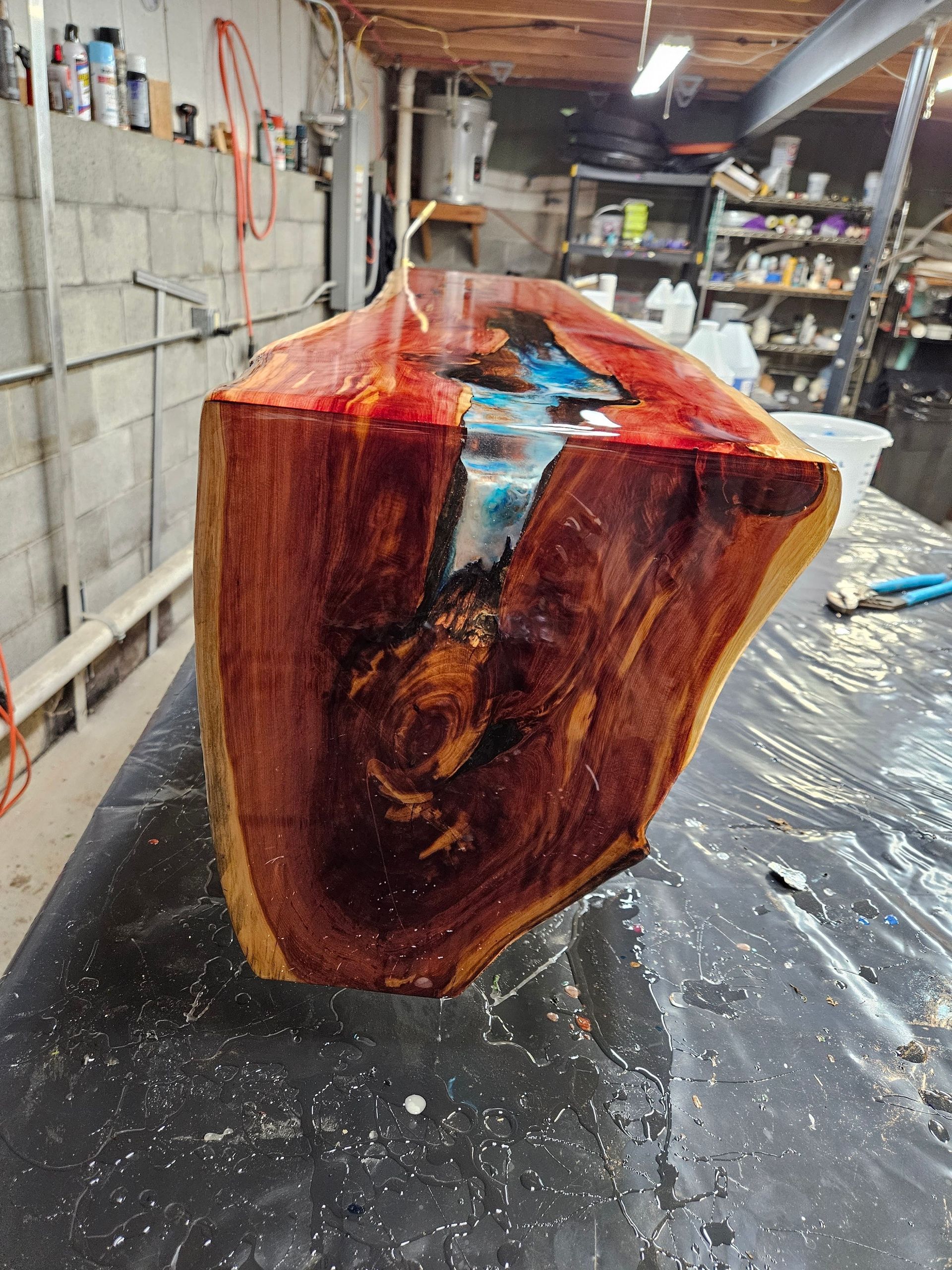 Glossy resin-coated wood slab on a workbench in a cluttered workshop